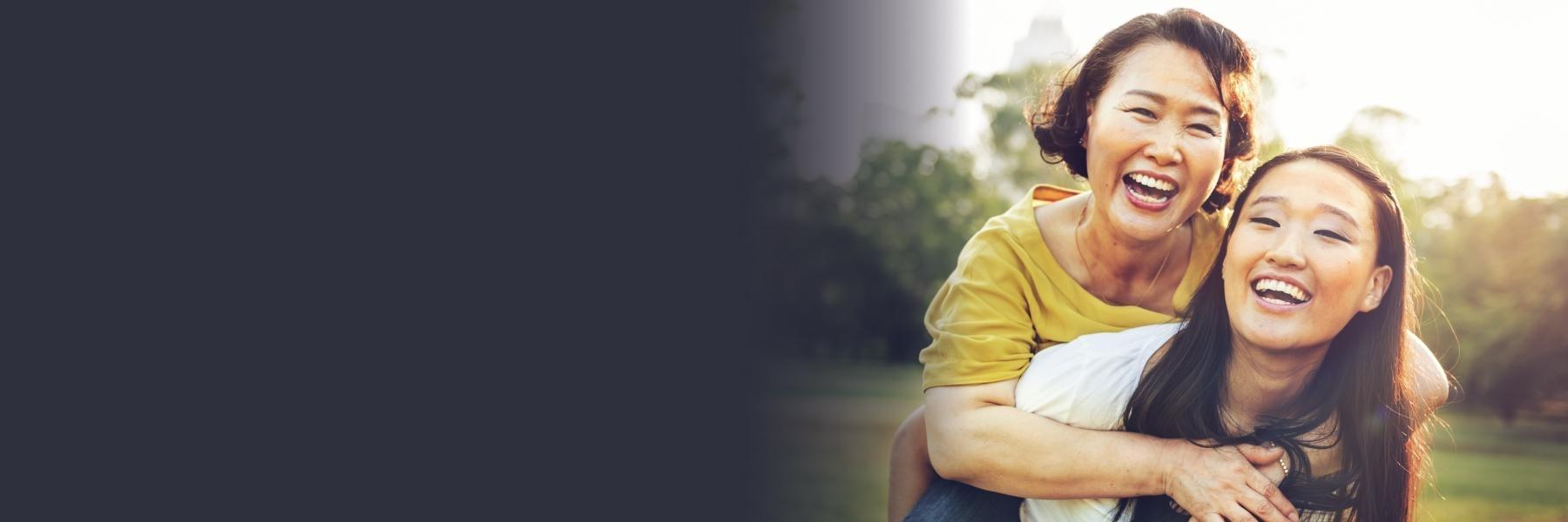 mother and daughter smiling and laughing in field 
