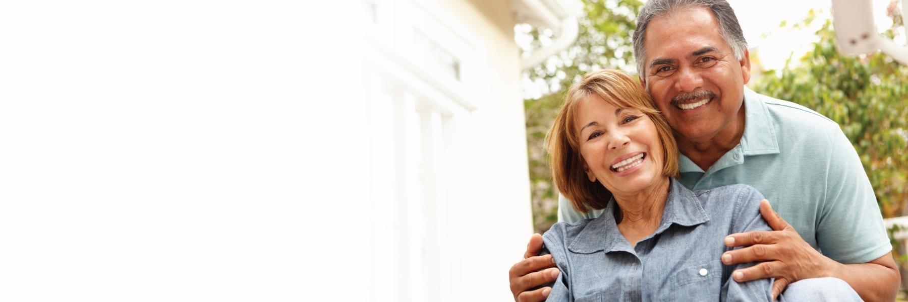 Older couple smiling with their new dental implants